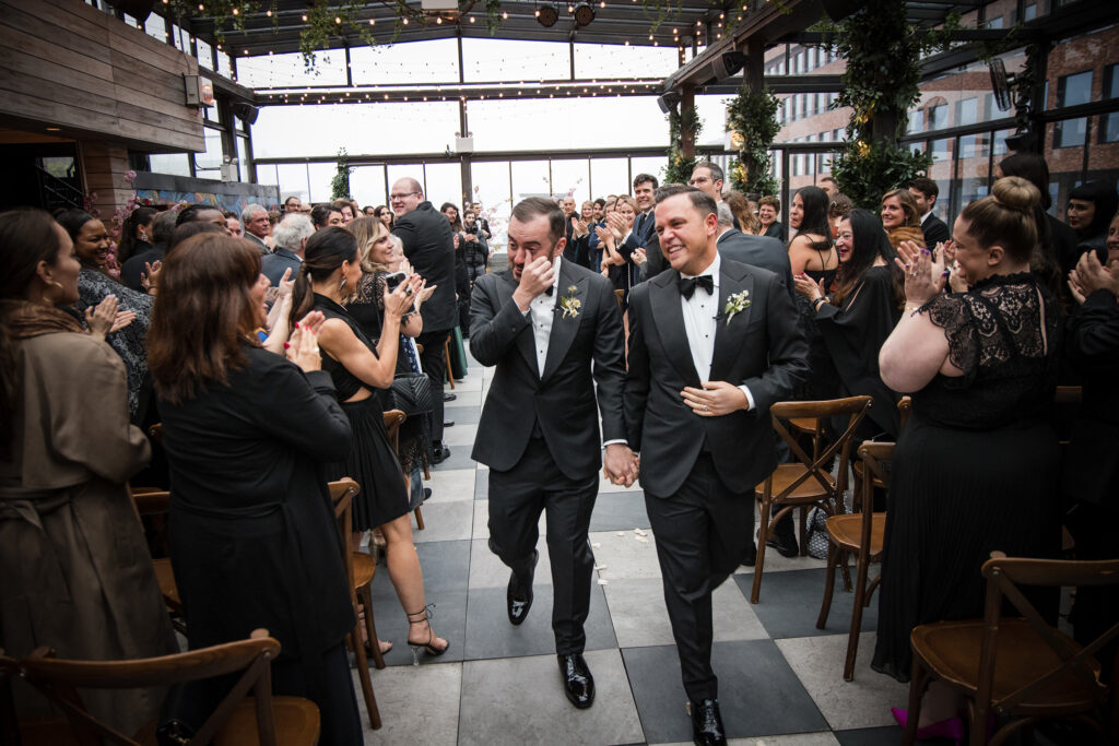 two grooms walking down the aisle after ceremony