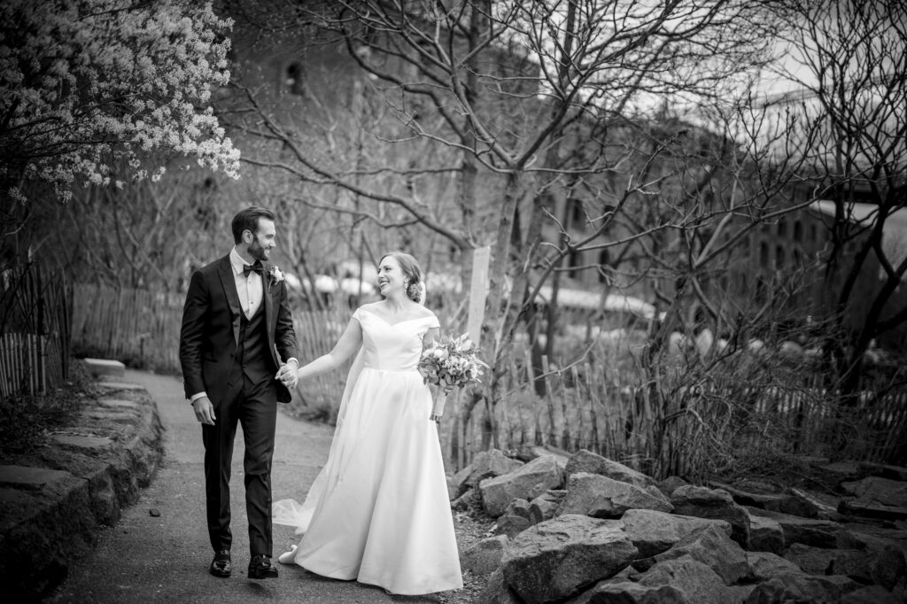 A bride and groom walking down a path in black and white at the River Cafe