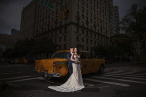 A bride and groom pose in front of a yellow taxi in NYC for their elopement.