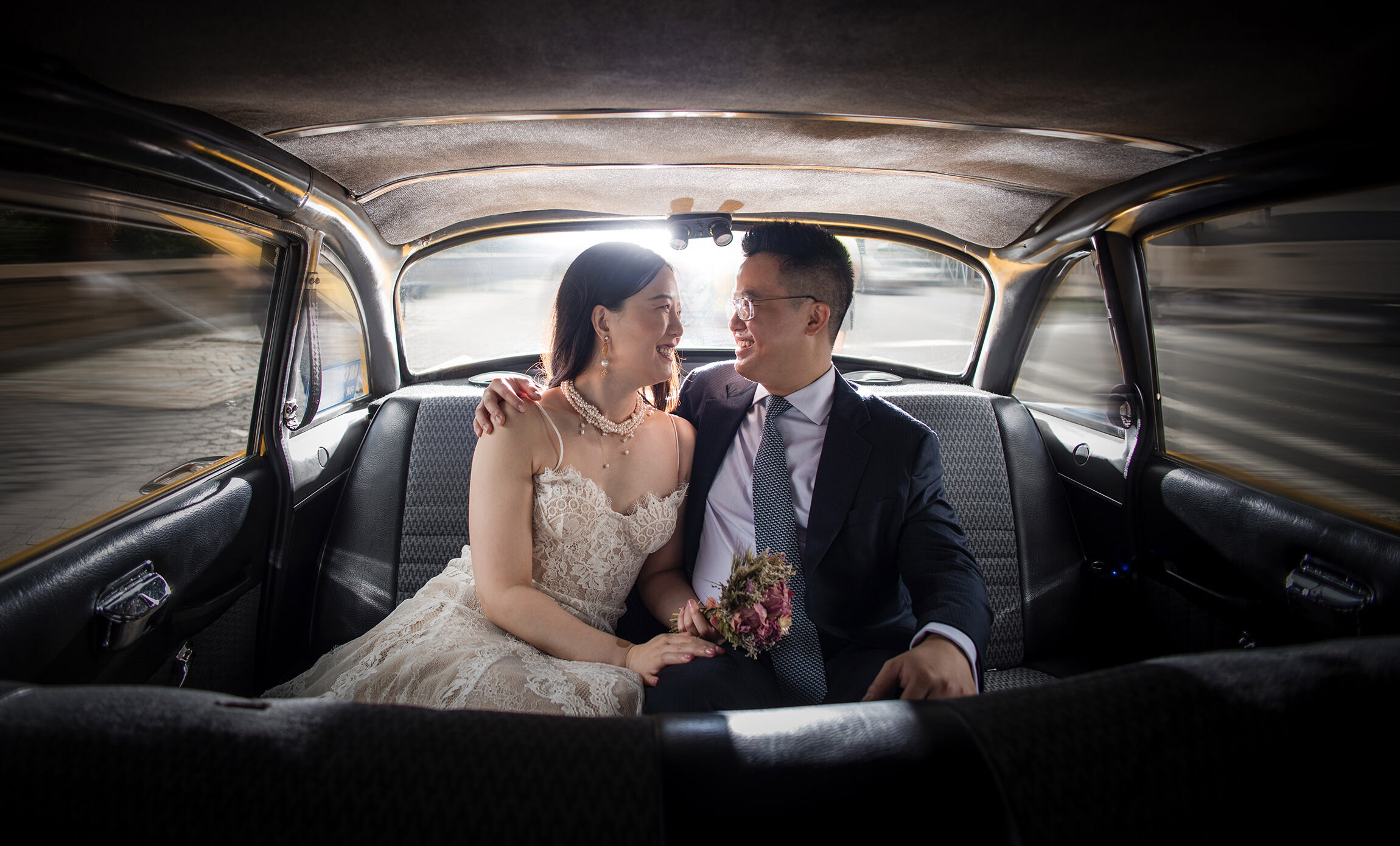 A bride and groom eloping in the back seat of a NYC taxi.
