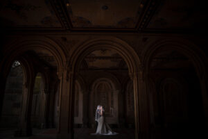 A bride in a wedding dress standing in a dark room, capturing the essence of an intimate elopement ceremony.