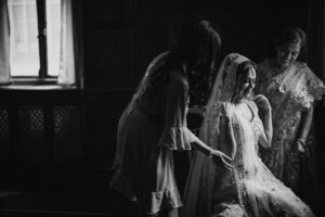 A black and white photo of a bride getting ready in a dark room at Gotham Hall.