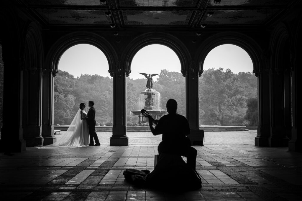 A NYC bride and groom listening to a street musician playing a violin in Central Park during their elopement.