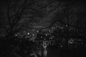 A black and white photo of a bride and groom in a park at night