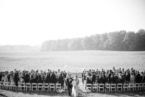 bride and groom walking away from wedding ceremony across field