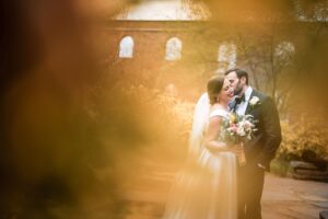 A bride and groom kissing in front of a brick building at the River Cafe