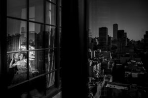 A black and white photo of a woman elopement out of a NYC window.