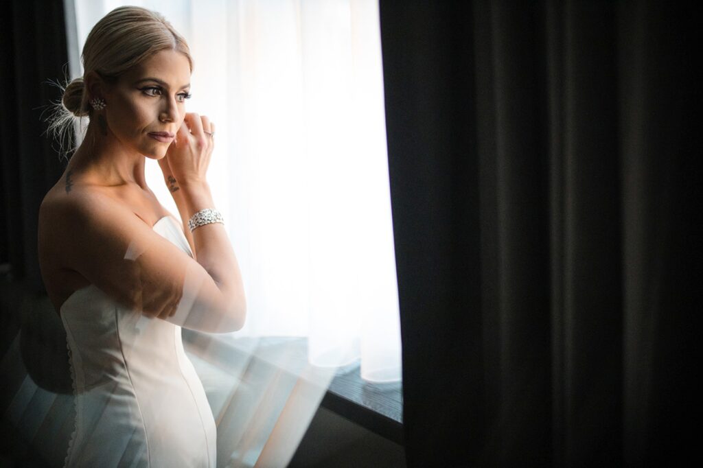 A bride from the Fitler Club is posing in front of a window.