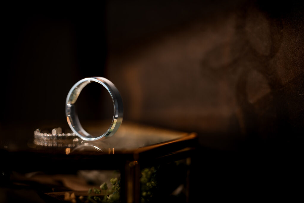 A wedding ring sits on a table in the sunlight.