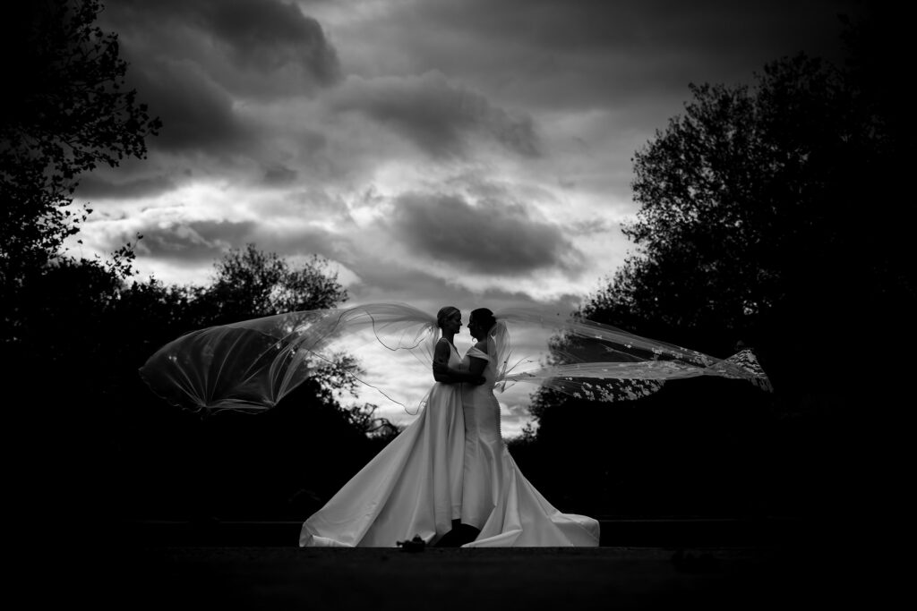 two brides in silhouette with veils flying in the wind