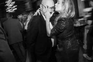 A man and woman kissing at a party.