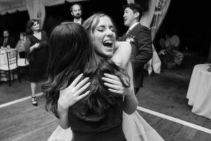 A bride hugging a friend on the dance floor.