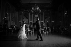 Black and white photo of a bride and groom dancing in a ballroom.