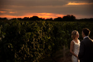 A bride and groom celebrating their wedding in the stunning vineyard of Bedell Cellars at sunset.