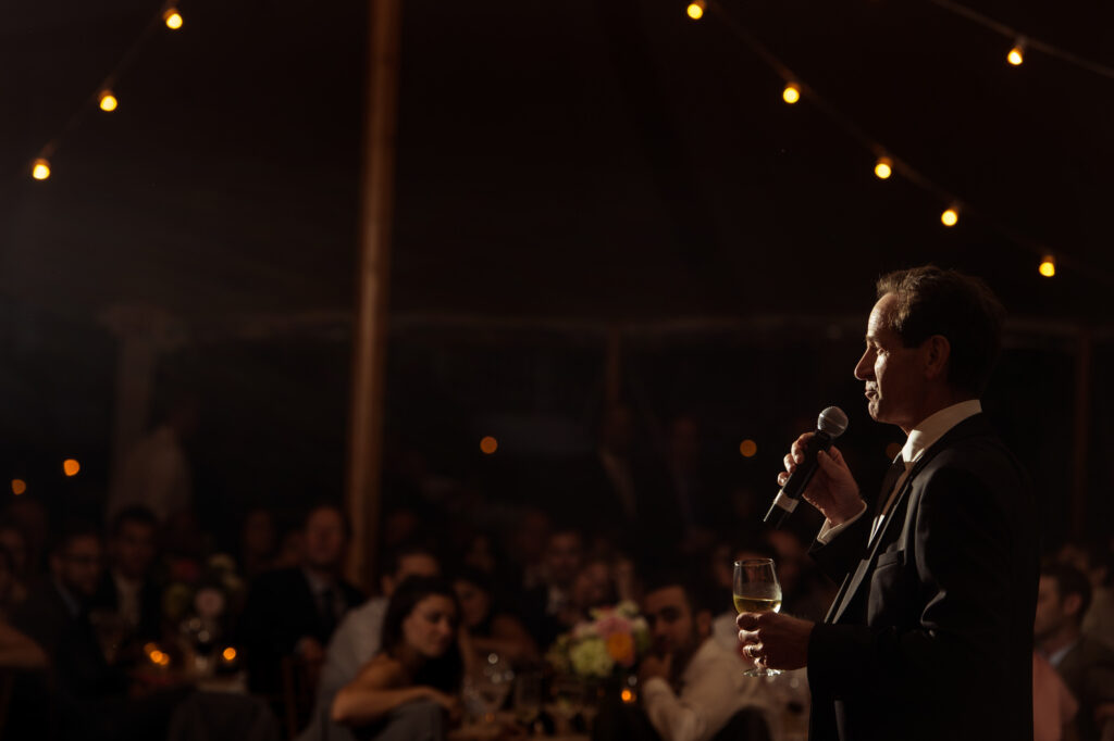 A man delivering a toast into a microphone at a Bedell Cellars wedding.
