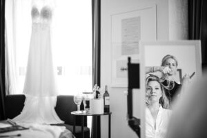 A bride is getting ready in a room with a mirror.