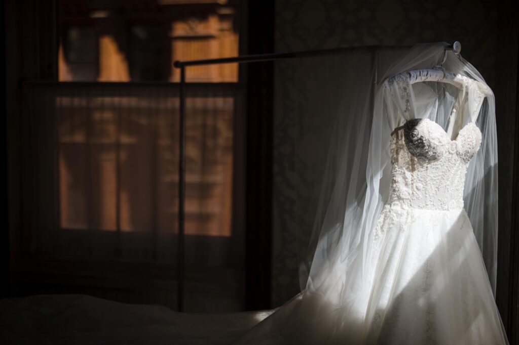 A wedding dress hangs on a rack in front of a window at Beekman Hotel in New York.