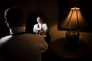 A man is getting ready for his wedding while standing in front of a mirror.