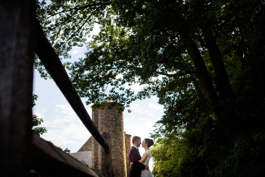A bride and groom standing on a bridge overlooking the scenic blue hill at stone barn.