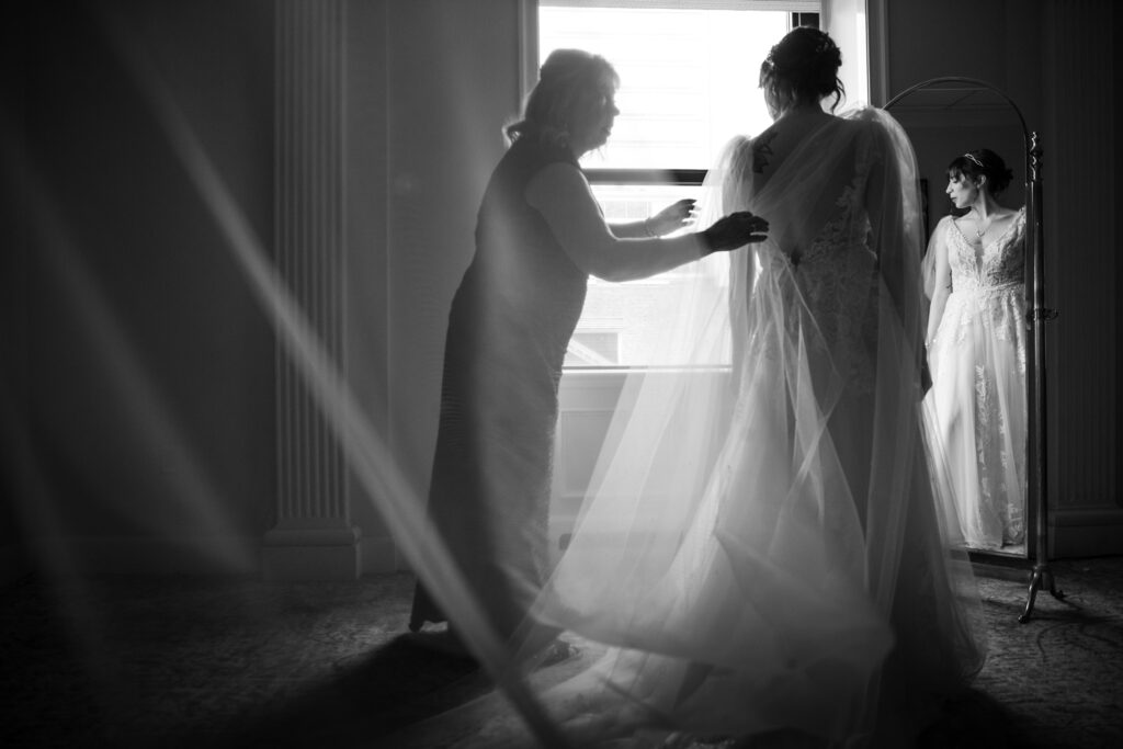 A bride is getting ready in front of a window.