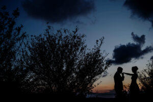 A silhouette of a couple holding hands at sunset during their blue hill wedding.