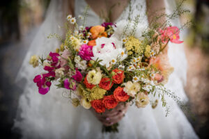 A bride holds a bouquet of colorful flowers at her wedding ceremony.