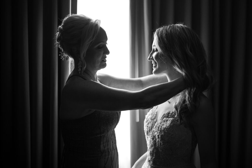 A friend is helping a bride put on her wedding dress.