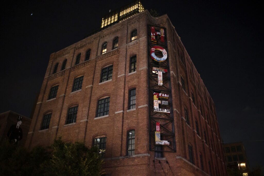 The Wythe Hotel, with its iconic sign, offers a stunning backdrop for a wedding ceremony amidst the enchanting atmosphere of the night.