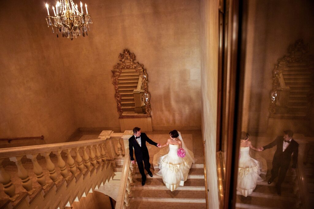 A bride and groom walking down the grand staircase at the Plaza Hotel for their elegant wedding ceremony.