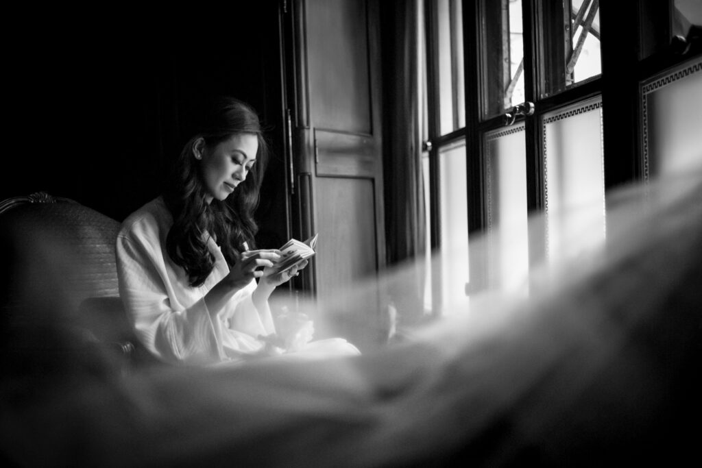 A bride is sitting in a window looking at a letter from her groom.