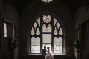 A bride and groom sitting in front of a window at Lyndhurst Mansion during their wedding ceremony.