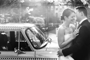 A wedding couple posing beside a vintage NYC cab.