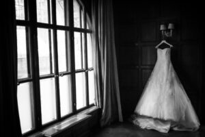 A black and white photo of a wedding dress hanging in front of a window at Cipriani.