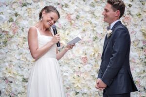 A bride and groom exchange their heartfelt vows in front of a stunning flower wall at a Wythe Hotel wedding.