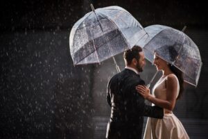 A Tribeca Rooftop wedding with a bride and groom holding umbrellas in the rain.