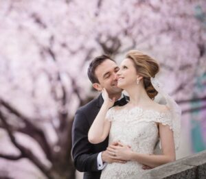 A couple celebrates their destination wedding with a romantic kiss in front of a stunning cherry blossom tree.