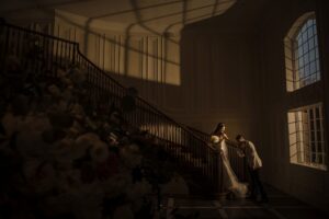 A bride and groom elegantly pose in front of a grand staircase at their Estate at Florentine Gardens wedding.
