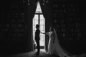 A bride and groom having a first look at their wedding in the Colony Club, NYC, with a beautiful bookcase as their backdrop.