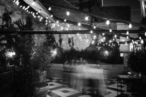 A black and white photo of a patio at the Wythe Hotel adorned with string lights.