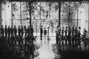 A roundhouse wedding where a bride and groom exchange vows in a room with a large window, basking in natural light.