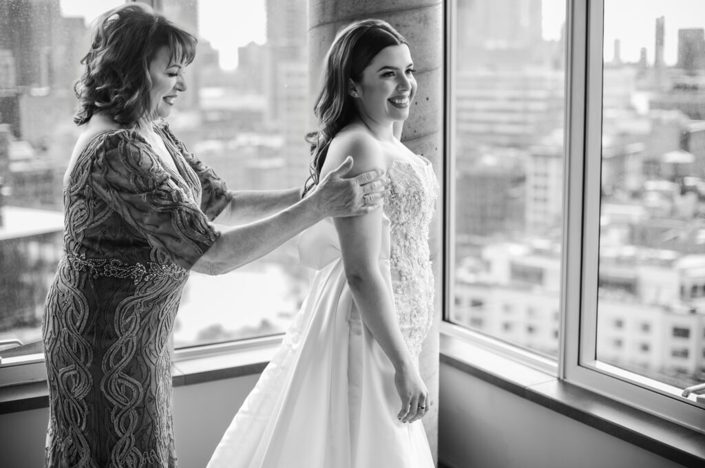 A mother assists her daughter in wearing her wedding dress, creating a special moment before the Modernhaus Soho ceremony.
