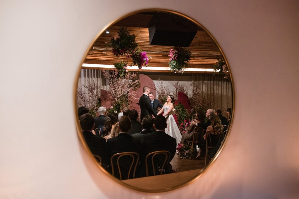 A bride and groom standing in front of a mirror during their Modernhaus wedding.