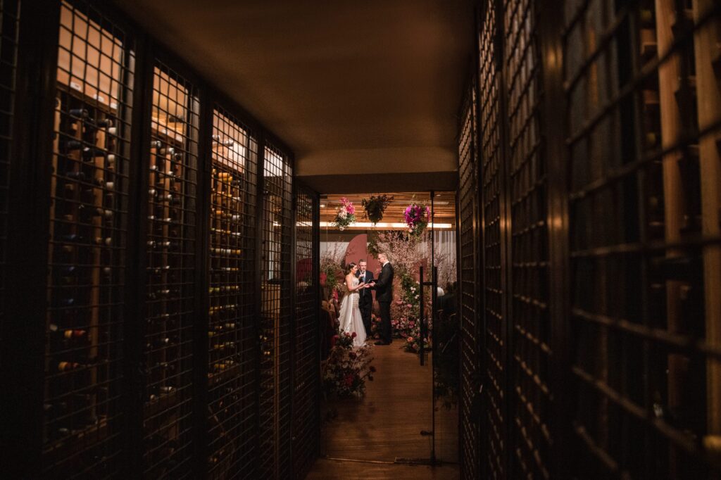 A bride and groom standing in a wine cellar, ready for their "Modernhaus Soho wedding" ceremony.