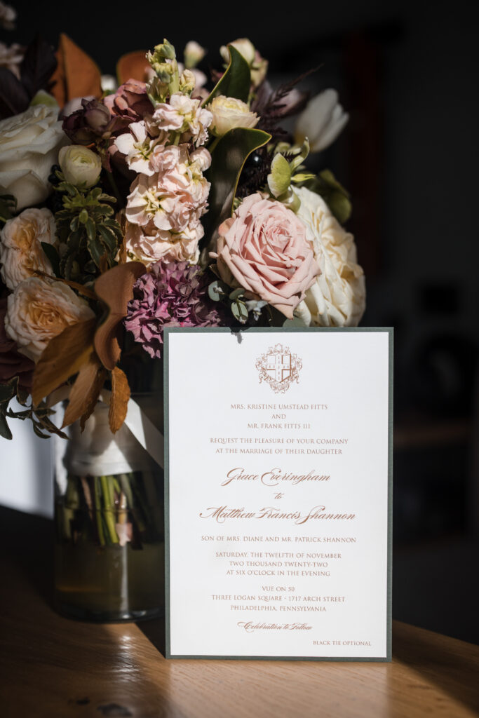 A wedding invitation adorns a table surrounded by flowers.