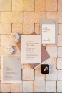 A collection of wedding invitations artfully displayed on a tiled wall.