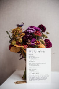 A bouquet of purple flowers, accompanied by a wedding program as a lovely memento.