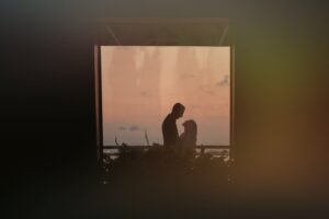 A silhouette of a man and woman standing in front of a window at their Liberty Warehouse wedding.
