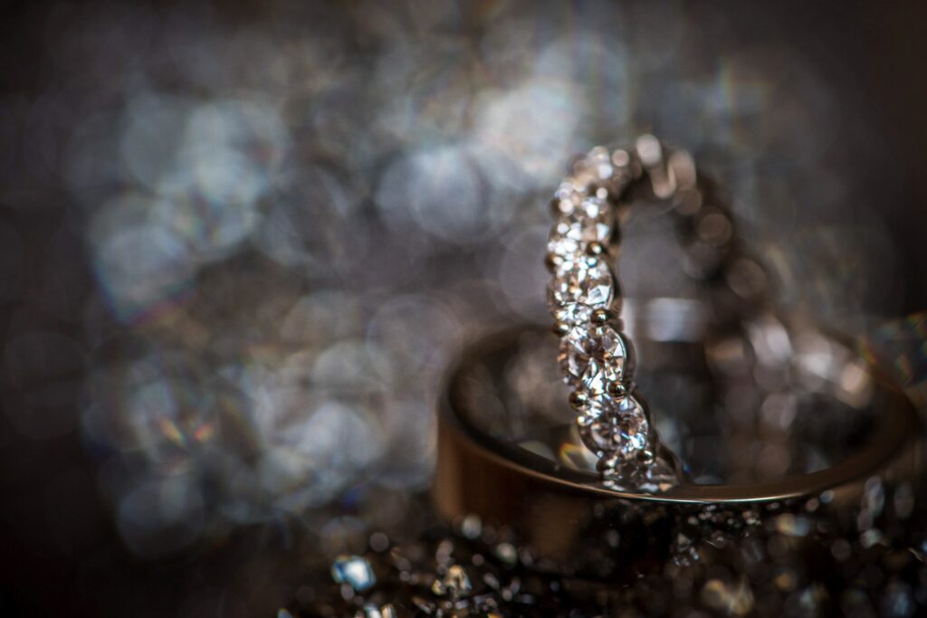 A wedding ring, adorned with exquisite diamonds, gracefully sits atop a luxurious pile of precious gems at The Pierre.