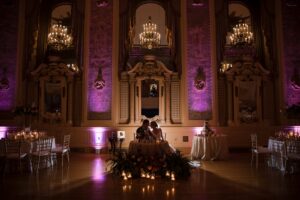 A wedding reception at Hotel duPont, an ornate ballroom illuminated by purple lighting.