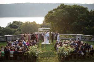 A Wave Hill wedding ceremony on a lawn overlooking a lake.